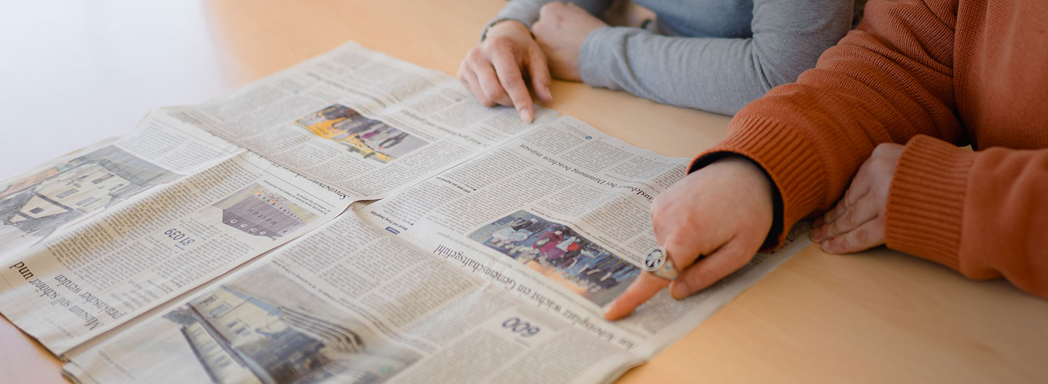 Zwei Menschen blättern zusammen in einer Zeitung