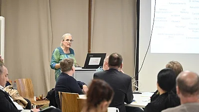 Eine Frau hält einen Vortrag und die Zuhörer schauen auf eine Leinwand