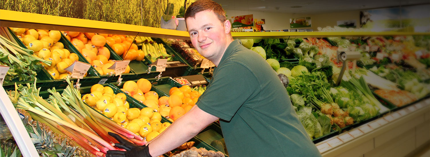Junger Mann räumt Obst in einem CAP-Markt ein